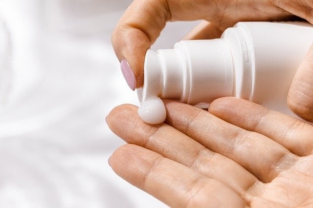 Close-up-view-of-a-pair-of-hands-squirting-some-face-lotion-from-a-white-bottle