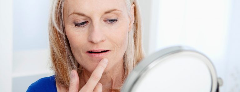 Woman examining wrinkles around mouth