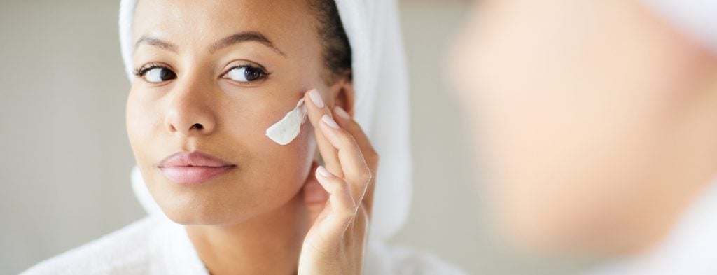 Woman applying moisturizer on face
